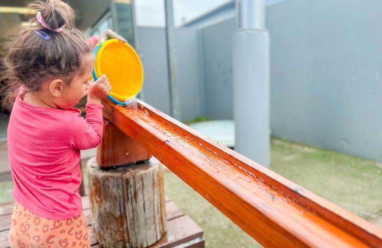 Evolve Education Preschool girl playing with water in playground at daycare