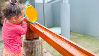Evolve Education Preschool girl playing with water in playground at daycare