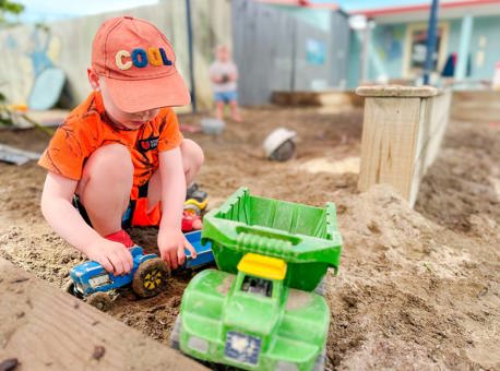 Evolve Education Preschool boy playing with trucks in the sandpit at daycare