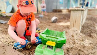 Evolve Education Preschool boy playing with trucks in the sandpit at daycare