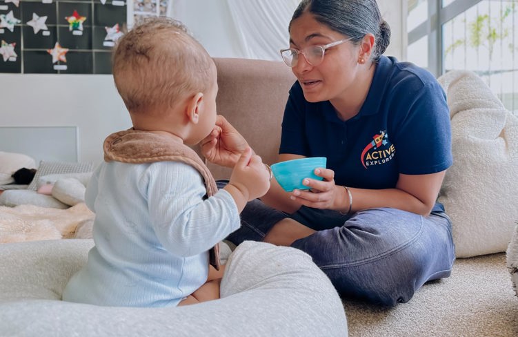 Evolve Education Teacher feeding baby boy in the nursery space at daycare