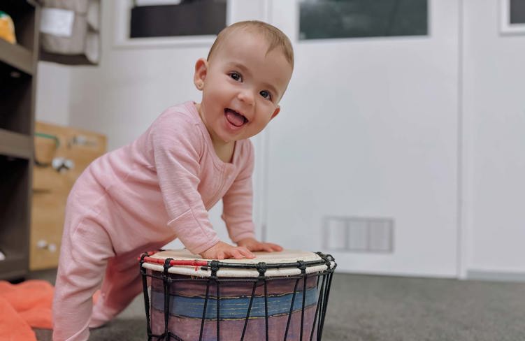 Evolve Education Baby girl playing with drum in nursery space at daycare